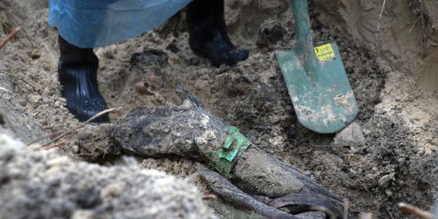 Part of the body of a Ukrainian soldier emerges from the ground during an excavation in the recently recaptured Izyum district of Ukraine, Friday, September 16, 2022. 