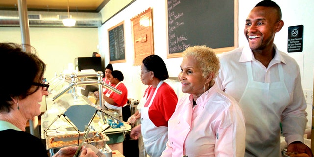 FILE - A customer picks up food from Sweetie Pie's owner Robbie Montgomery, second right, and Montgomery's son, James "Tim" Norman, right, at the shop in St. Louis, on April 19, 2011. 