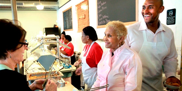 FILE - A customer picks up food from Sweetie Pie's owner Robbie Montgomery, second right, and Montgomery's son, James "Tim" Norman, right, at the shop in St. Louis, on April 19, 2011. 