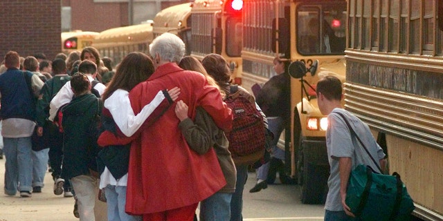 Students arriving at Heath High School in West Paducah, Ky., embrace an unidentified adult on Tuesday, Dec. 2, 1997, after student Michael Carneal opened fire at the school the day before, leaving three students dead and five wounded.