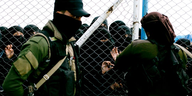 FILE - Women speak to guards at the gate at Al-Hol camp in Hasakeh province, Syria, March 31, 2019. 