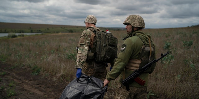 Ukrainas Nacionālās gvardes karavīri pirmdien, 2022. gada 19. septembrī, apgabalā netālu no Krievijas robežas, Harkovas apgabalā, nēsā somu, kurā atradās Ukrainas karavīra līķis. 