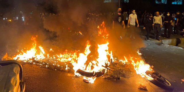 Une moto de police brûle lors d'une manifestation contre la mort d'une jeune femme qui avait été arrêtée pour avoir enfreint le code vestimentaire conservateur du pays, dans le centre-ville de Téhéran, en Iran. (AP Photo)