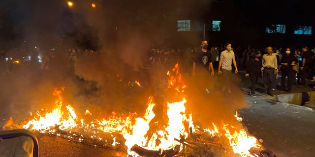 A police motorcycle burns during a protest over the death of a young woman who had been detained for violating the country's conservative dress code, in downtown Tehran, Iran. (AP Photo)