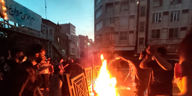 معترضان در جریان اعتراض به مرگ زنی که توسط پلیس اخلاق در مرکز شهر تهران، ایران بازداشت شده بود، آتش می زنند و خیابان را مسدود می کنند. 