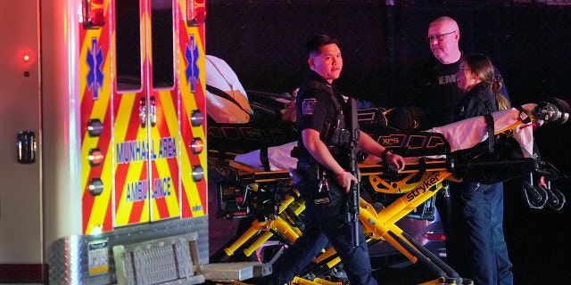 A law enforcement officer walks past an EMS crew on the scene at Kennywood Park, an amusement park in West Mifflin, Pa., early Sunday, Sept 25, 2022.