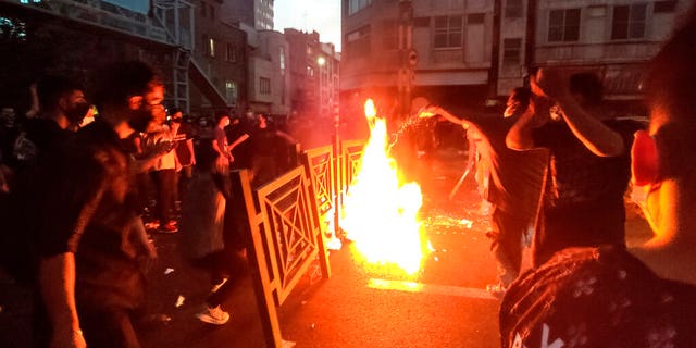 In this Wednesday, Sept. 21, 2022, photo taken by a person not employed by the Associated Press and obtained by AP outside Iran, protesters set fires and block a street during a protest over the death of a woman who was arrested by the moral police, in the center of Tehran, Iran. 