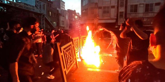 Protesters catch fire and block the street during a protest over the death of a woman who was arrested by the moral police in central Tehran, Iran. 