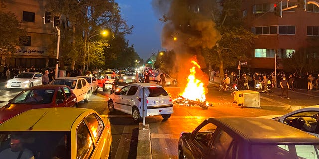 In this Sept. 19, 2022, photo taken by an individual not employed by the Associated Press and obtained by the AP outside Iran, a police motorcycle burns during a protest over the death of a young woman who had been detained for violating the country's conservative dress code, in downtown Tehran, Iran. 