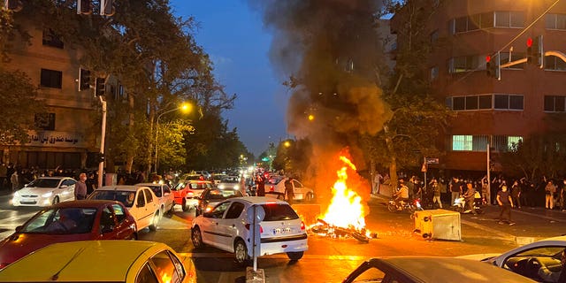 A police motorcycle burns during a protest over the death of a young woman who had been detained for violating the country's conservative dress code, in downtown Tehran, Iran, Sept. 19, 2022.