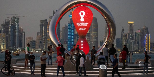 People gather around the official countdown timer showing the time remaining until kickoff of the 2022 World Cup, in Doha, Qatar
