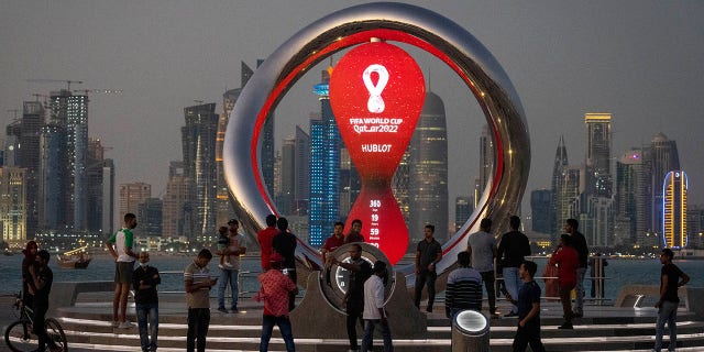 People gather around the official countdown clock showing the time remaining until the start of the 2022 World Cup, in Doha, Qatar, on November 25, 2021.