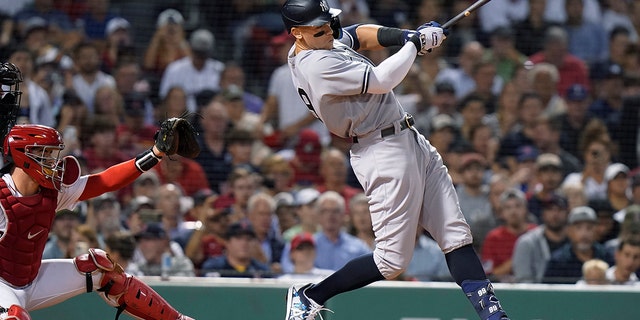 New York Yankees' Aaron Judge, right, singles next to Boston Red Sox's Reese McGuire during the third inning of a baseball game Tuesday, Sept. 13, 2022, in Boston.