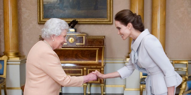 Angelina Jolie presented with the Insignia of an Honorary Dame Grand Cross of the Most Distinguished Order of St Michael and St George by Queen Elizabeth II in 2014 at Buckingham Palace, London. Jolie is receiving an honorary damehood (DCMG) for services to UK foreign policy and the campaign to end war zone sexual violence. 