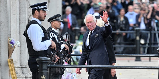 King Charles III waves to the public after viewing floral tributes to the late Queen Elizabeth II outside Buckingham Palace on Sept. 9, 2022.