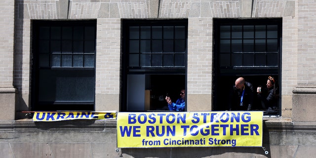 Spectators look out of their window during the 126th Boston Marathon on April 18, 2022 in Boston.
