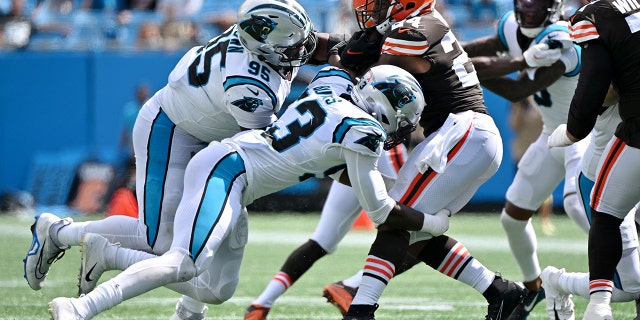Nick Chubb #24 of the Cleveland Browns is tackled by Derrick Brown #95 and Brian Burns #53 of the Carolina Panthers during the third quarter at Bank of America Stadium on September 11, 2022 in Charlotte, North Carolina.
