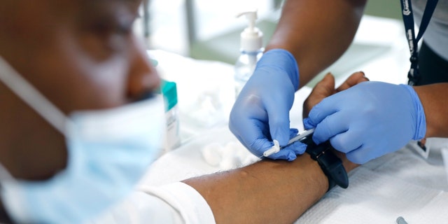 David Hightower, 57, left, looks away while receiving the monkeypox vaccine by registered nurse Jeremy Oyague, right, with The Los Angeles Department of Public Health at a vaccination clinic to immunize people against monkeypox and COVID at The Village Mental Health Services in Los Angeles, a site run by The People Concern. 