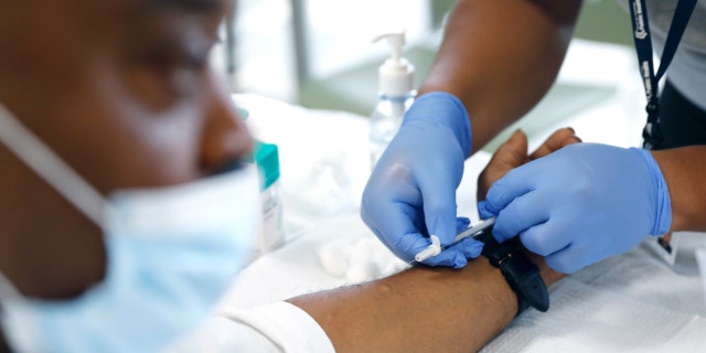 David Hightower, 57, left, looks away while receiving the monkeypox vaccine by registered nurse Jeremy Oyague, right, with The Los Angeles Department of Public Health at a vaccination clinic to immunize people against monkeypox and COVID at The Village Mental Health Services in Los Angeles, a site run by The People Concern.