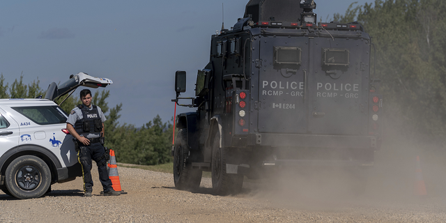 An armored RCMP vehicle, right, drives past a police roadblock set up on the James Smith Cree First Nation reservation in Saskatchewan, Canada, on Tuesday, Sept. 6, 2022, as they search for a suspect in a series of stabbings. 