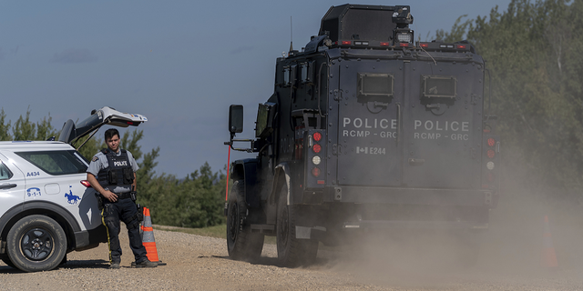 An armored RCMP vehicle, right, drives past a police roadblock set up on the James Smith Cree First Nation reservation in Saskatchewan, Canada, on Tuesday, Sept. 6, 2022, as they search for a suspect in a series of stabbings.