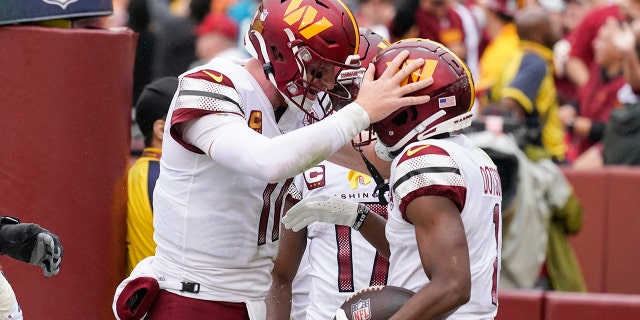 Washington Commanders quarterback Carson Wentz, #11, celebrates with wide receiver Jahan Dotson, #1, after scoring a touchdown against the Jacksonville Jaguars in the first half of an NFL football game, Sunday, Sept. 11, 2022, in Landover, Maryland.