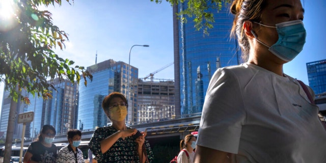 Commuters wearing face masks walk along a street in the central business district in Beijing, Thursday, Sept. 1, 2022.