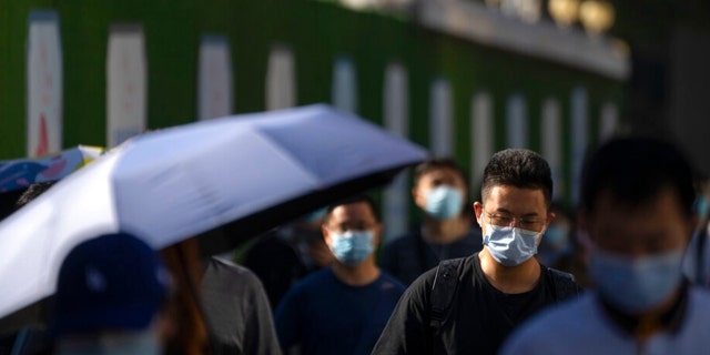 Commuters wearing face masks walk along a street in the central business district in Beijing, Thursday, Sept. 1, 2022. 