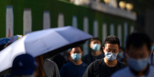 Commuters wearing face masks walk along a street in the central business district in Beijing, Thursday, Sept. 1, 2022.