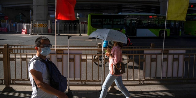 Commuters wearing face masks walk through a highway underpass in the central business district in Beijing, Thursday, Sept. 1, 2022. 