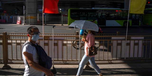 Commuters wearing face masks walk through a highway underpass in the central business district in Beijing, Thursday, Sept. 1, 2022.
