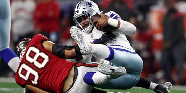 Anthony Nelson, número 98 do Tampa Bay Buccaneers, Dak Prescott, número 4 do Dallas Cowboys, é relatado durante o segundo tempo no AT&T Stadium  T em 11 de setembro de 2022 em Arlington, Texas.