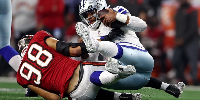 Anthony Nelson, número 98 do Tampa Bay Buccaneers, Dak Prescott, número 4 do Dallas Cowboys, é relatado durante o segundo tempo no AT&T Stadium  T em 11 de setembro de 2022 em Arlington, Texas.