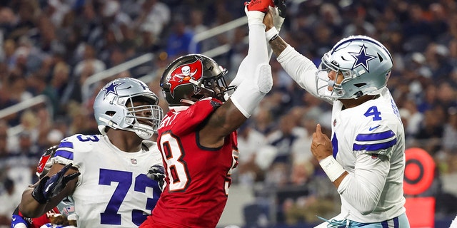 Dallas Cowboys quarterback Dak Prescott, #4, hits his hand against Tampa Bay Buccaneers linebacker Shaquil Barrett, #58, while throwing during the fourth quarter at AT&T Stadium in Arlington, Texas, Sept. 11, 2022.