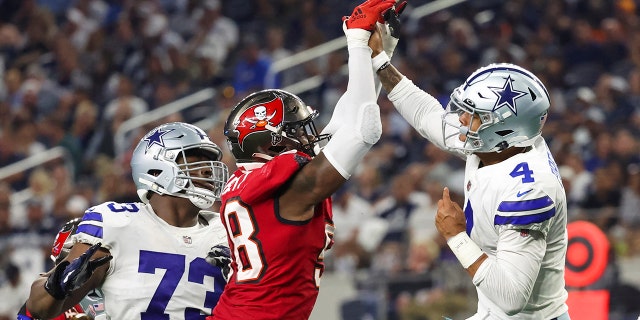 Dallas Cowboys quarterback Dak Prescott, #4, hits his hand against Tampa Bay Buccaneers linebacker Shaquil Barrett, #58, while throwing during the fourth quarter at AT&T Stadium in Arlington, Texas, Sept. 11, 2022.