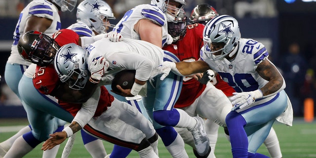 Tampa Bay Buccaneers linebacker Devin White, left, sacks Dallas Cowboys quarterback Dak Prescott, #4, as Tony Pollard, #20, looks on in the second half of a NFL football game in Arlington, Texas, Sunday, Sept. 11, 2022.