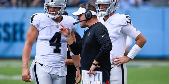 Las Vegas Raiders head coach Josh McDaniels, center, talks with quarterback Derek Carr (4) in the second half of a game against the Tennessee Titans Sept. 25, 2022, in Nashville. 