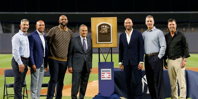 Baseball Hall of Famer Derek Jeter (3rd from right) poses for a photograph with his Hall of Fame plaque along with former teammates, from left, Jorge Posada, Mariano Rivera, CC Sabathia, former manager Joe Torre, Andy Pettitte and Tino Martinez before a game against the Tampa Bay Rays at Yankee Stadium Sept. 9, 2022, in the Bronx borough of New York City.