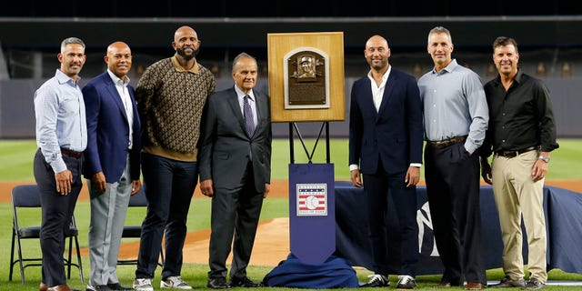 Baseball Hall of Famer Derek Jeter (3rd from right) poses for a photograph with his Hall of Fame plaque along with former teammates, from left, Jorge Posada, Mariano Rivera, CC Sabathia, former manager Joe Torre, Andy Pettitte and Tino Martinez before a game against the Tampa Bay Rays at Yankee Stadium Sept. 9, 2022, in the Bronx borough of New York City.