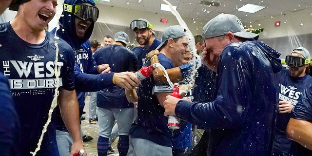 Los Angeles Dodgers celebrate in the locker room after a 4-0 win in a baseball game against the Arizona Diamondbacks in Phoenix, Tuesday, Sept. 13, 2022. The Dodgers clinched the National League West.