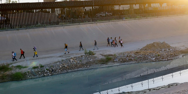 Asylum-seeking migrants, mostly from Venezuela, walk near the border wall after crossing the Rio Bravo to turn themselves in to U.S. Border Patrol agents to request asylum in El Paso, Texas, U.S., as seen from Ciudad Juarez, Mexico, Sept. 17, 2022. 