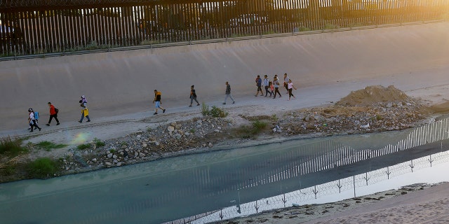 Asylum-seeking migrants, mostly from Venezuela, walk near the border wall after crossing the Rio Grande to turn themselves in to U.S. Border Patrol agents to request asylum in El Paso, Texas, as seen from Ciudad Juarez, Mexico, Sept. 17, 2022. 