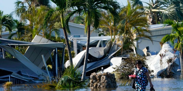 Holly Nugyn walks out of her flooded neighborhood after Hurricane Ian passed by the area Thursday, Sept. 29, 2022, in Fort Myers, Florida.