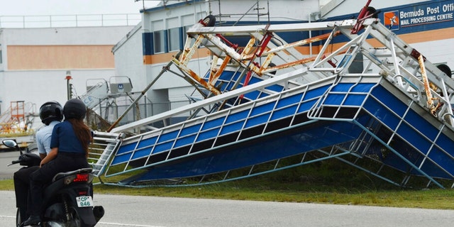 A motorcyclist rides past a structure turned on its side in the aftermath of Hurricane Fiona, in St. George, Bermuda, Friday, Sept. 23, 2022. 