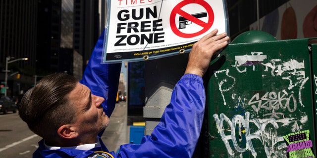 A New York Police Department public affairs officer sets up signs reading Gun Free Zone around Times Square in New York on Wednesday, Aug. 31, 2022.