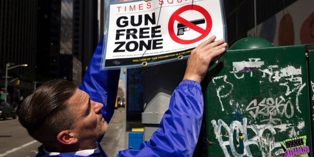 A New York Police Department public affairs officer sets up signs reading Gun Free Zone around Times Square in New York on Wednesday, Aug. 31, 2022.