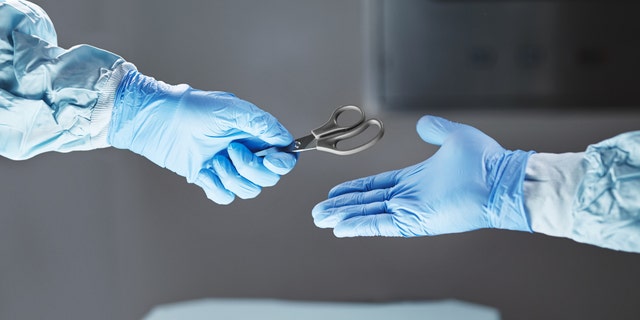 Cropped shot of a surgeon passing a pair of scissors to his colleague.