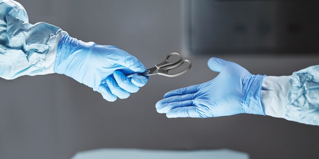 Cropped shot of a surgeon passing his colleague a pair of scissors.