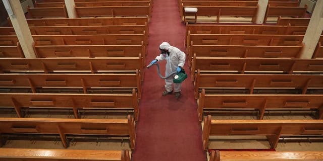 David Rossini with Bostonian Cleaning and Restoration of Braintree cleans the aisle at St. Gregory's Church in Dorchester, Massachusetts, during the COVID-19 pandemic on May 18, 2020.