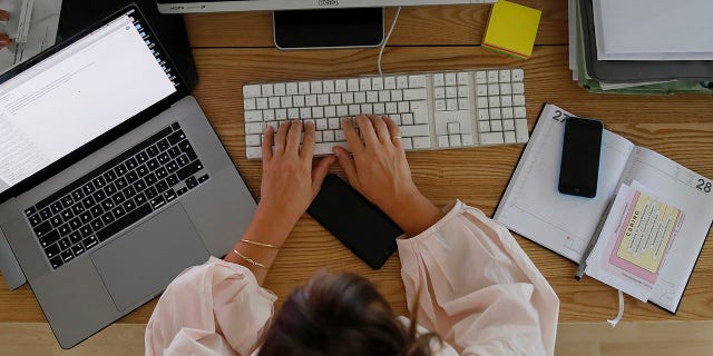 A woman is shown working at a desktop computer in a home office.?